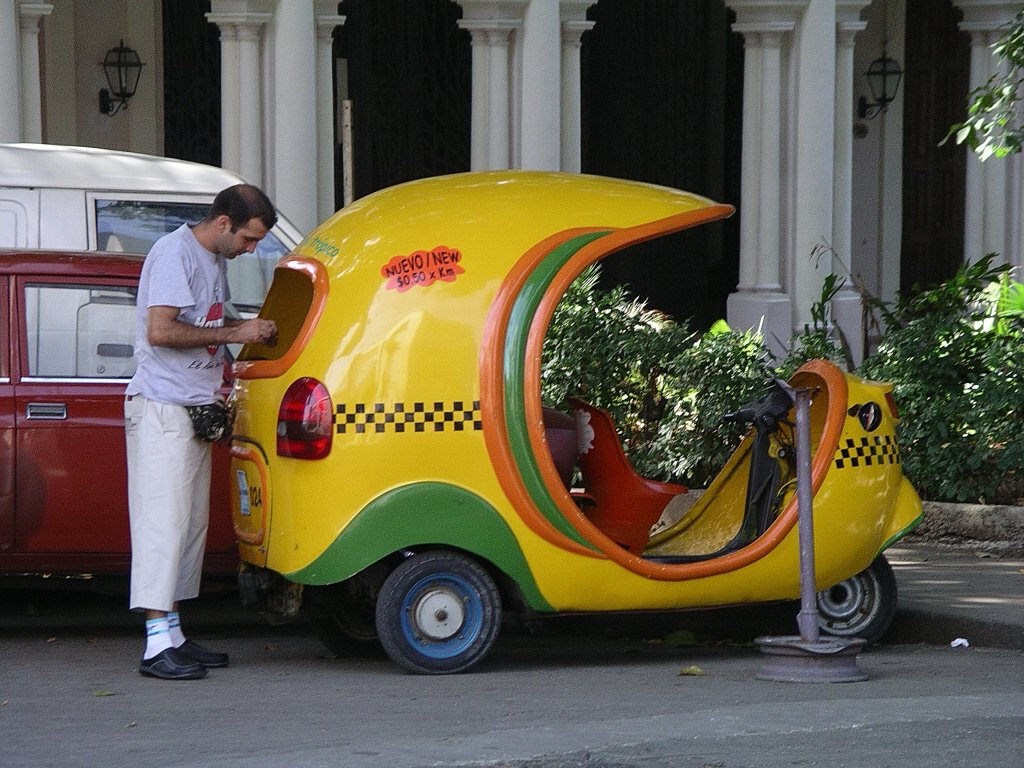Coco-Taxi. 
Die gnstige kubanische Art Taxi zu fahren. Zwei Personen und der Fahrer knnen in den dem an eine Kokosnuss erinnernden (daher der Name) Gefhrt auf Vespa-Basis mitfahren.
 
Habana
09-2003