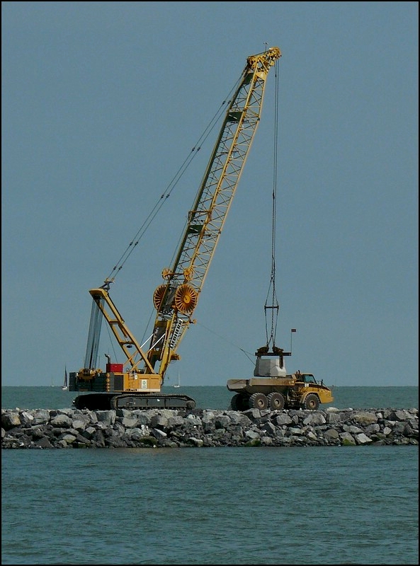 Die Betonblcke werden von einem Liebherr Raupenkran an der Baustelle in der Hafeneinfahrt von Oostende im Wasser positionniert. 11.08.2010