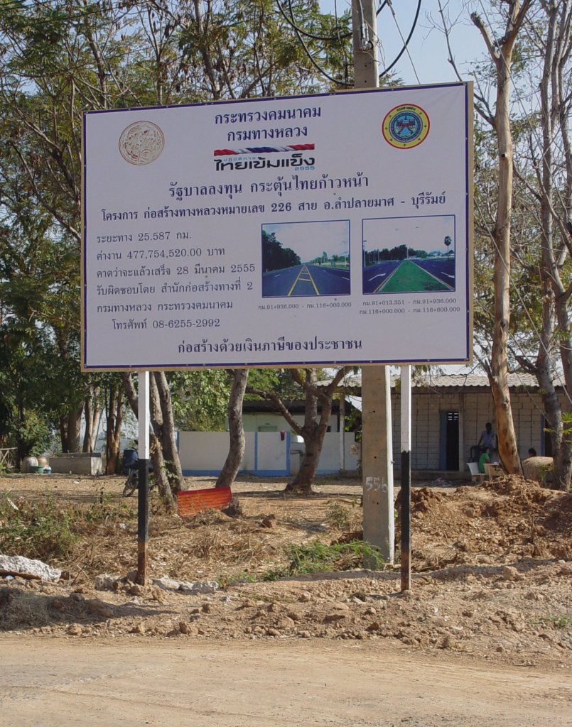 Dies Schild steht seit einiger Zeit in Lamplaimat im Nordosten Thailands und erlutert den Ausbau der Straenverbindung zwischen Buri Ram, der Provinzhauptstadt und Lamplaimat von bisher 2 Fahrspuren auf 4 Fahrspuren