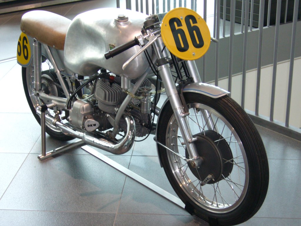 DKW 350 RM. 1952 - 1956. Hier wird eine Rennmaschine des Jahrganges 1953 gezeigt. Der vom Chefkonstrukteur der Motorradrennabteilung (Erich Wolf) konstruierte 3-Zylinder V-motor, leistete 38 PS bei maximal 12.000 U/min. 
Hier wurden Geschwindigkeiten bis zu 190 km/h erreicht. Aufgrund der hohen Drehzahlen, die der Motor klaglos verkraftete, wurde das Motorrad auch die  singende Sge  genannt. In den 1950´er Jahren dominierte dieses Motorrad den Motorradrennsport in Europa. Audi Museum Ingolstadt.