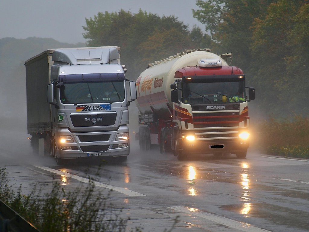 MAN mit Planenauflieger am 19.10.2010 im strmenden Regen auf der A4 bei Aachen Richtung Niederlndische Grenze unterwegs. Der Fahrer im Scania  Silozug auf der linken Spur riskiert gerade 80 Euro und einen Punkt fr berholen im LKW berholverbot.