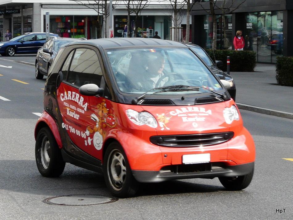 Rot - Schwarzer Smart mit Werbung unterwegs in der Stadt Zug am 10.04.2010