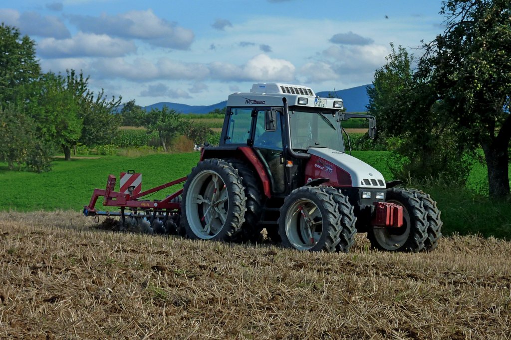 Steyr M-trac spezial 75, mit angebauter Scheibenegge bei der Arbeit, die Doppelbreifung erhht die Traktion, Aug.2011
