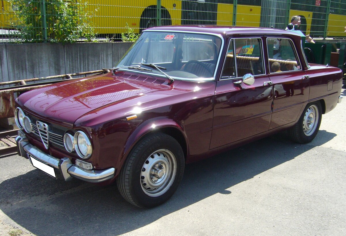 Alfa Romeo Giulia 1300 ti, gebaut in den Jahren von 1966 bis 1972. Mit der viertürigen Giulia hatte Alfa Romeo ab 1962 einen Verkaufsschlager gelandet. Es gab zum Verkaufsstart zwei Motorisierungen mit 1.3l und 1.6l Hubraum. Mit dem 1300 ti brachten die Marke aus Milano ein sportliches Modell für den weniger betuchten Kunden auf den Markt. Der Vierzylinderreihenmotor mit doppelter Nockenwelle hat einen Hubraum von 1290 cm³ und leistet 82 PS. Oldtimertreffen an der  Alten Dreherei  in Mülheim an der Ruhr am 17.06.2023.