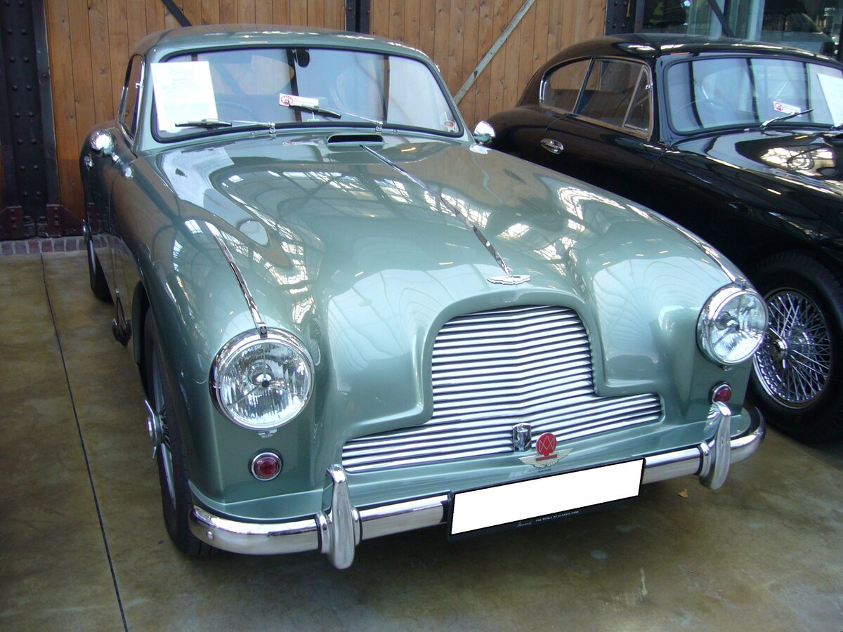 Aston Martin DB2/4 MK I Saloon aus dem Jahr 1955 im Originalfarbton seagreen. Produziert wurde das Modell in den Jahren von 1953 bis 1955. Hier wird einer der letzten Wagen dieser Baureihe gezeigt, da er im Mai 1955 erstmalig in der englischen Gemeinde Martons zugelassen wurde. Er ist mit einem Sechszylinderreihenmotor ausgerüstet, der aus einem Hubraum von 2922 cm³ serienmäßig 142 PS leistet. Durch einige technische Verfeinerungen leistet dieses Auto allerdings 180 PS und kann den Wagen, je nach gewählter Getriebeübersetzung, auf bis zu 225 km/h beschleunigen. Classic Remise Düsseldorf am 30.11.2023.