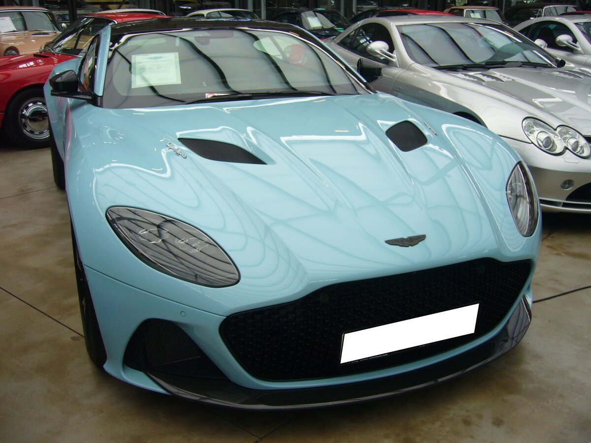 Aston Martin DBS Superleggera. Im Juni 2018 wurde der Sportwagen als Nachfolger des Aston Martin Vanquish vorgestellt. Auch bei diesem Modell finden sich in der Typenbezeichnung die Buchstaben DB wieder. Die Initialien von Aston Martin  Urgestein  David Brown. Unter der Haube dieses zukünftigen Klassikers ist ein V12-Motor mit Twin-Turbo-Aufladung verbaut. Dieser Motor hat einen Hubraum von 5204 cm³ und leistet 725 PS. Damit kann dieser, im Porsche Farbton gulf blau lackierte DBS Superleggera eine Höchstgeschwindigkeit von 340 km/h erreichen. Classic Remise Düsseldorf am 26.02.2024.