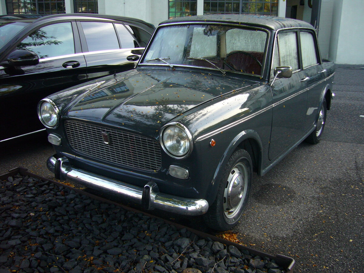 Fiat 1100D, wie er von 1962 bis 1966 vom Band lief. Der  Nuova Millecento  wurde bereits 1953 vorgestellt und in etlichen Serien permanent modifiziert. Im April 1962 schickten die Turiner den 1100D ins Rennen. Das D steht hier aber nicht für Diesel, sondern für DERIVAZIONE (Ableitung), da die Karosserie nach einem umfangreichen  Facelifting  auch motorentechnisch aufgerüstet wurde. Für den deutschen und Benelux-Markt wurden die Fahrzeuge (nur die Limousinen) bei NSU-Fiat in Heilbronn montiert. Der Vierzylinderreihenmotor hatte nun einen Hubraum von 1221 cm³ und leistete nun 50 PS. Besucherparkplatz der Düsseldorfer Classic Remise am 28.09.2021.