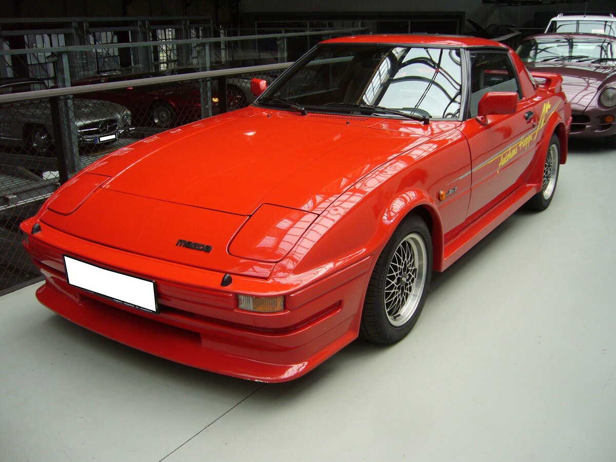 Mazda RX7, wie er (mit Facelifts) von 1978 bis 1985 gebaut wurde. Der RX7 schien dem 1975 vorgestellten Porsche 924 aus dem Gesicht geschnitten zu sein. Ein solcher RX7 mit reichhaltiger Serienausstattung kostete bei seiner Markteinführung in Deutschland DM 22990,00. Angetrieben wird 2+2 Sitzer von einem Zweischeibenwankelmotor mit einem Kammervolumen von zwei mal 573 cm³. Dieser Kreiskolbenmotor leistet 115 PS und kann den Wagen auf bis zu 200 km/h Höchstgeschwindigkeit beschleunigen. Classic Remise Rüsseldorf am 07.06.2021.