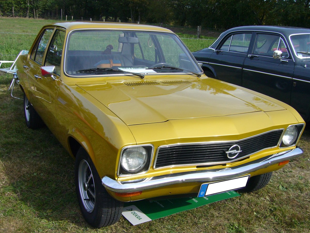 Opel Ascona A als viertürige Limousine, gebaut von 1970 bis 1975. Das völlig neue Modell sollte die Lücke zwischen dem Einsteigermodell Kadett und dem Mittelklassemodell Rekord füllen. Der Wagen stand ab November 1970 bei den Händlern. Hier wurde ein Ascona im Farbton DD Gold abgelichtet, wie er ab September 1973 produziert wurde. Dieses ist am schwarzen Kunststoffkühlergrill zu erkennen. Der Erstbesitzer hat als Motorisierung für diesen Wagen die Motorversion 1.6 gewählt. Der Vierzylinderreihenmotor hat einen Hubraum von 1584 cm³ und leistet 68 PS. Ein solch viertüriger Ascona A war ab DM 10.345,00 zu haben. Oldtimertreffen des Oldtimerclubs Schermbeck am 22.09.2019 in Lühlerheim.
