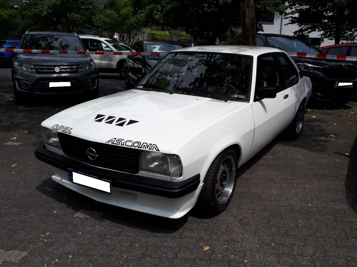Opel Ascona B in der Karosserieversion zweitürige Limousine im Farbton polarweiß. Der glattflächige Ascona B wurde auf der IAA des Jahres 1975 vorgestellt. Er war als zwei- und viertürige Limousine lieferbar. Das Modell war mit etlichen Motorisierungen, sogar einem Dieselmotor, lieferbar. Der gezeigte Ascona B ist mit etlichen sportlichen Features, wie zum Beispiel den damals sehr beliebten ATS-Cup-Felgen ausgestattet. 1981 wurde die Produktion zu Gunsten des Nachfolgers Ascona C eingestellt. Oldtimertreffen in Siegen am 19.06.2022.
