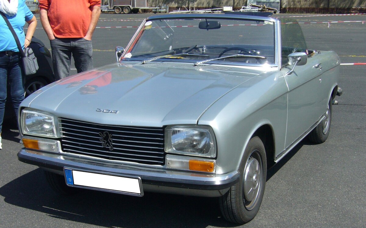 Peugeot 304S Cabriolet im Farbton gris clair, produziert in den Jahren von 1970 bis 1975 im Werk Sochaux. Das 304 Cabriolet basierte auf der bereits im Jahr 1969 erschienen 304´er Limousine. Während die Limousine und das Break genannte Kombimodell, auch mit einem Dieselmotor geordert werden konnten, waren das Coupe und das Cabriolet nur mit einem Benzinmotor lieferbar. Dieser Vierzylinderreihenmotor mit einem Hubraum von 1288 cm³ leistet bis zum Modelljahr 1973 65 PS. Ab dem Modelljahr 1974 erhöhte sich die Leistung auf 75 PS. Von den insgesamt 9.500 produzierten 304S Cabriolets wurden ca. 1.800 Stück in Deutschland verkauft. Der Kaufpreis betrug in der Grundausstattung DM 10.400,00 inclusive eines serienmäßigen Hardtopdaches. French Car Devotion am 30.04.2023 an Mo´s Bikertreff in Krefeld.