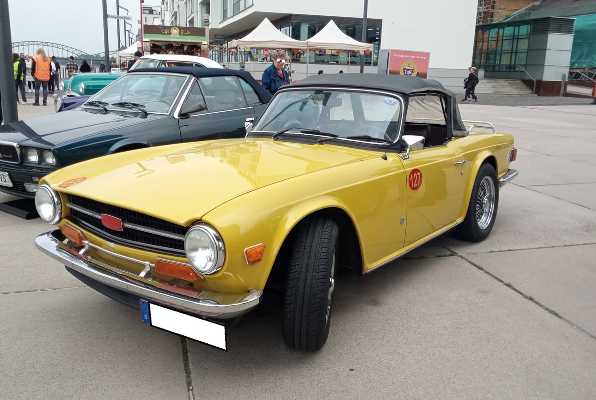 Triumph TR6 im Farbton mimosa yellow, produziert in den Jahren von 1970 bis 1975. Im Jahr 1970 erschien der letzte Abkömmling der klassischen Triumph TR-Baureihe in Form des TR6. Die Karosserie hatte der legendäre Giovanni Michelotti (*1921 +1980) gezeichnet. Der Sechszylinderreihenmotor des TR6 stammt vom Triumph 2000 und wurde auf 2498 cm³ Hubraum aufgebohrt. Dieser Motor leistet 150 PS und beschleunigt den TR6 auf eine Höchstgeschwindigkeit von 190 km/h. Rheinpromenade Köln am 24.09.2022.