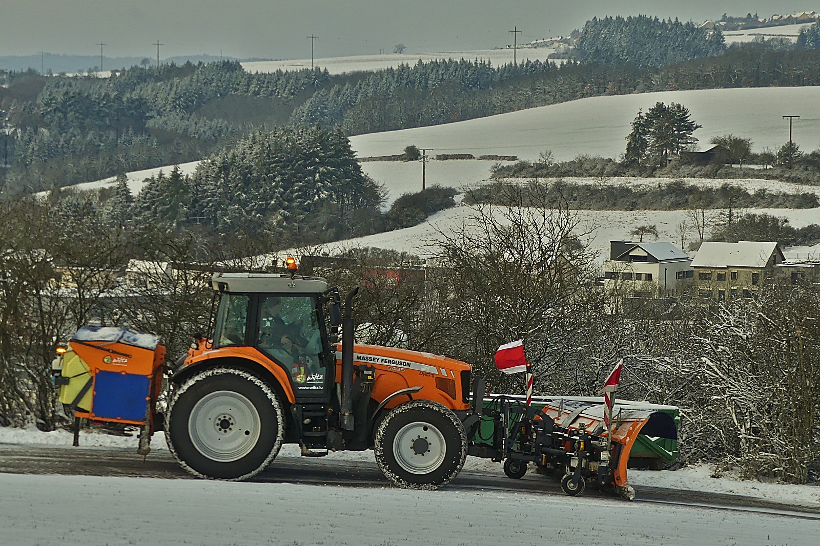 Massey Ferguson 6465, mit Schneeschieber und Salzstreuer im Einsatz beim Winterbetrieb auf der Nebenstraßen der Gemeinde Wiltz. 18.01.2024