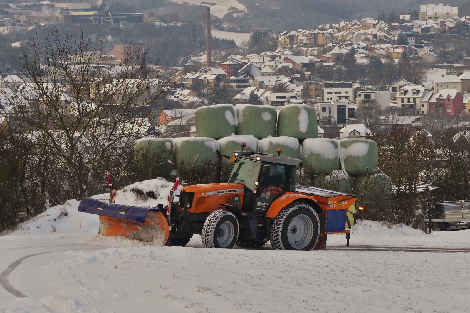 Massey Ferguson 6465, mit Schneeschieber und Salzstreuer im Einsatz beim Winterbetrieb auf der Nebenstraßen der Gemeinde Wiltz. 18.01.2024