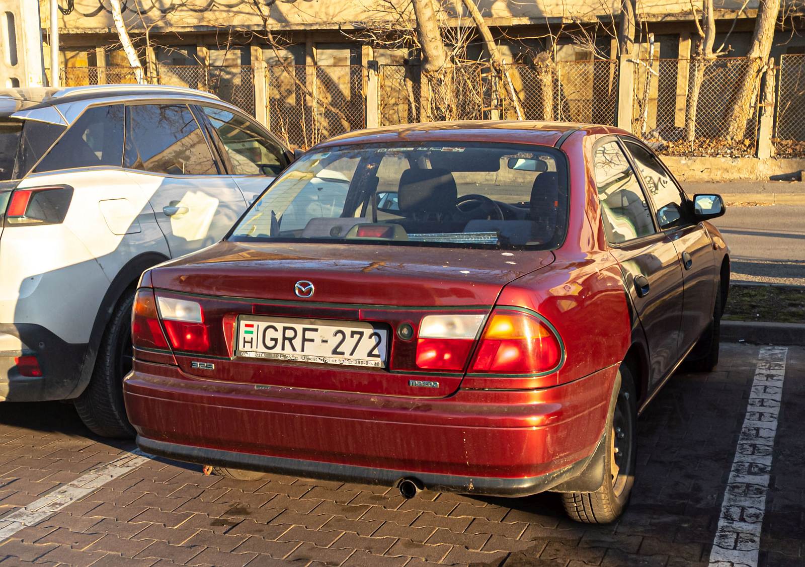 Rückanischt: roter Mazda 323 Sedan, der fünften Generation . Foto: 03.2022.
