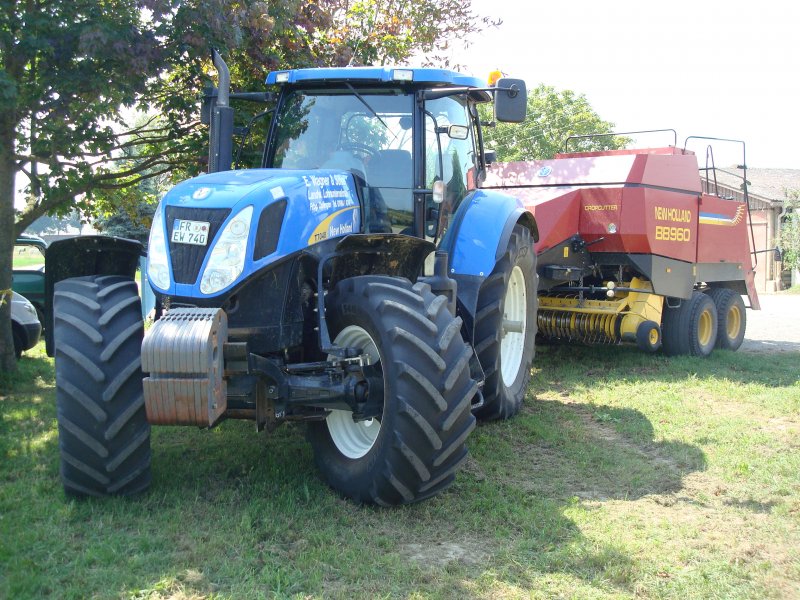 schwerer Traktor der Firma New Holland,
Typ T7040 Turbo-Diesel mit 6800ccm und 218PS angehngt eine Rundballenpresse CROPCUTTER BB960
Aug.2009 bei Freiburg