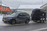 BMW X5 mit Pferdetransportanhänger, hält am Straßenrand.