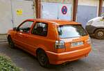 Rückansicht: dreitürer VW Golf III in Orange.