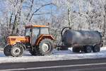 Deutz Traktor mit hoffentlich leerem Güllefass, steht nahe einer Straßenbaustelle im Schnee.