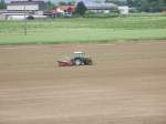 Von der Ferne betrachtet wirkt dieser Fendt Traktor auf dem groen Feld ganz klein und verloren.