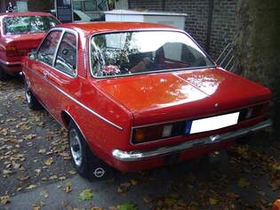 Heckansicht einer zweitrigen Opel Kadett C Limousine im Farbton brilliantrot.