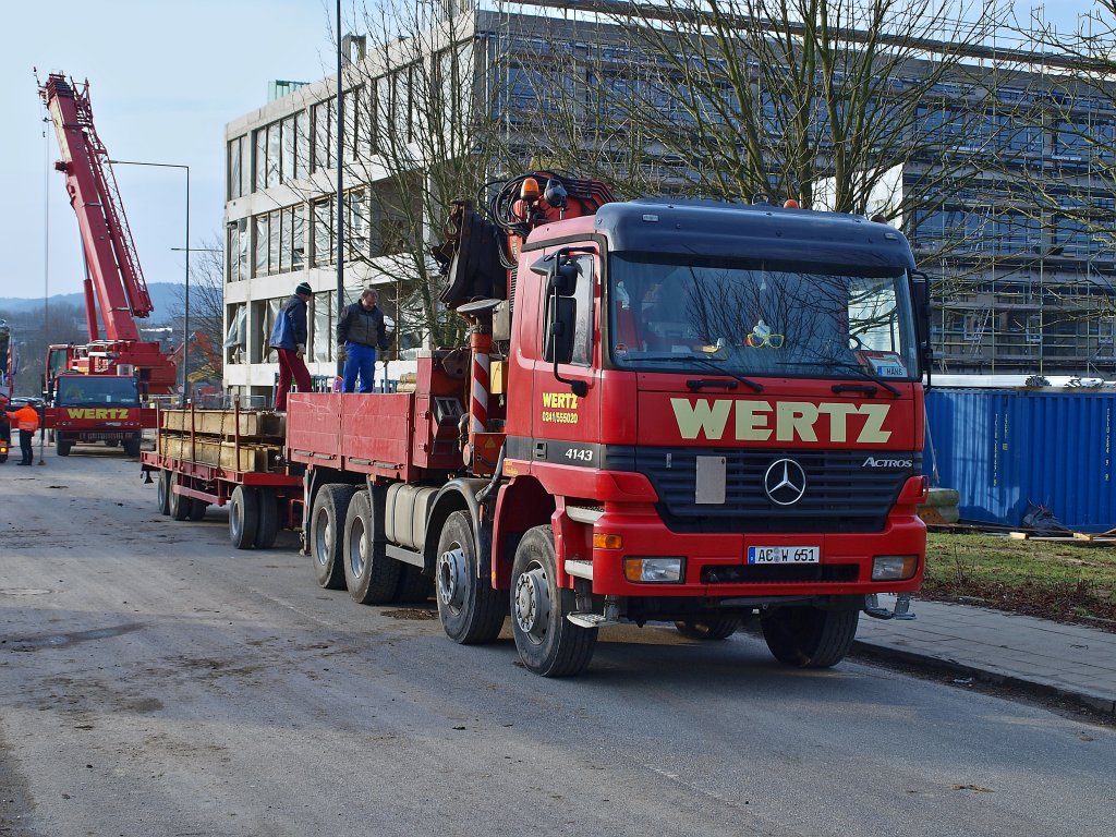 Actros 4143 mit Kranaufbau und 3achs Tiefladeanhnger der Firma Wertz aus Aachen am 14.02.2011 an der Campusbaustelle. Im Hintergrund  wird ein Kran der selben Firma gerade aufgebaut.