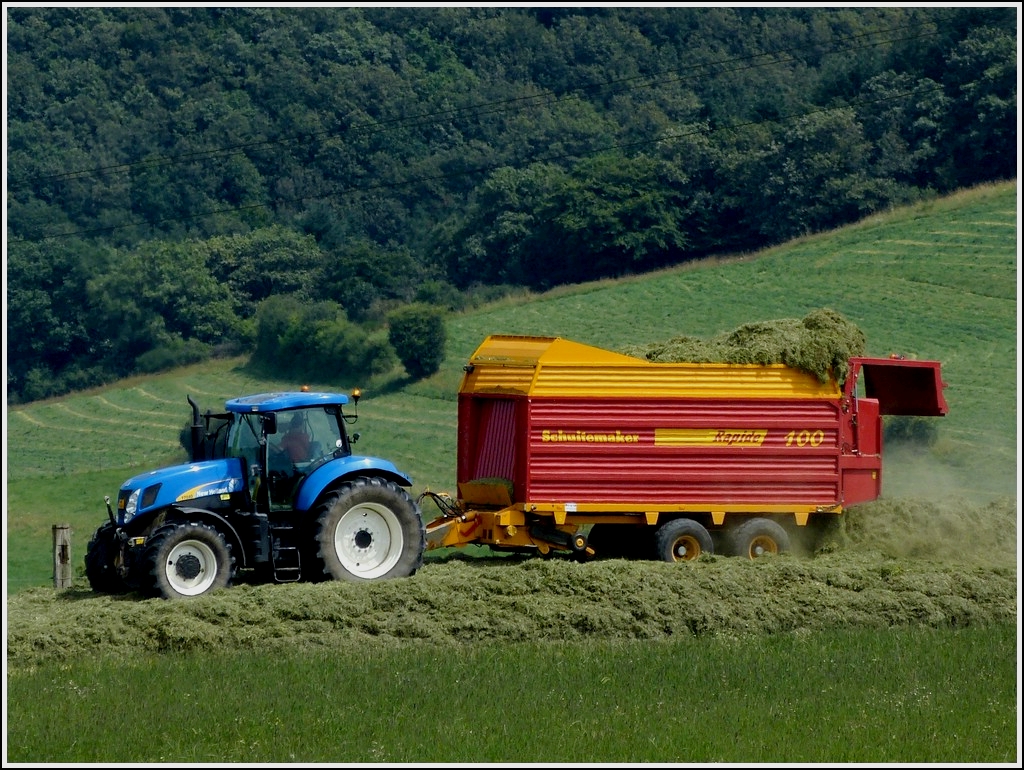 Der New Holland Traktor zieht den Selbstladewagen ber den Silohaufen wo er diesen entleert. 24.07.2012