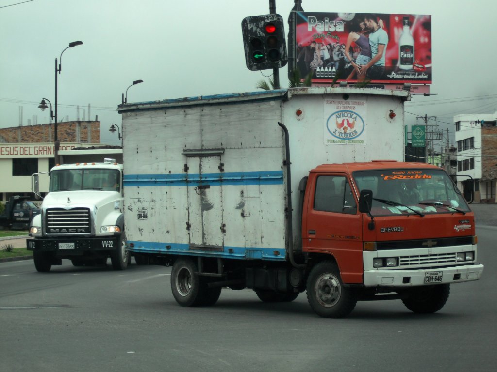 Ein alter Chevrolet NPR biegt am 07.02.2011 in Ibarra, Ecuador vor einem Mack Truck ab.