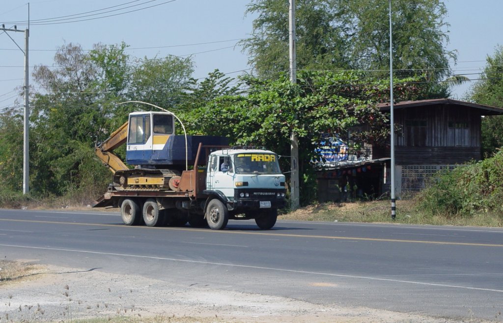 Ein MITSUBISHI Lkw mit einem KOMATSU-Bagger auf der Ladeflche am 28.01.2011 im Nordosten Thailands.