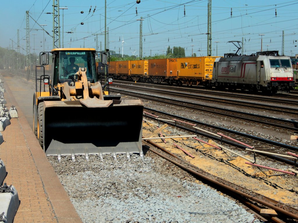 Mit einem Caterpillar 966H Radlader wird am 25.04.2011 neuer Schotter in das Gleisbett von Gleis 2 in Aachen West gefahren und planiert. Im Hintergrund Crossrail 185 580-8 (Jana) mit einem Containerzug.