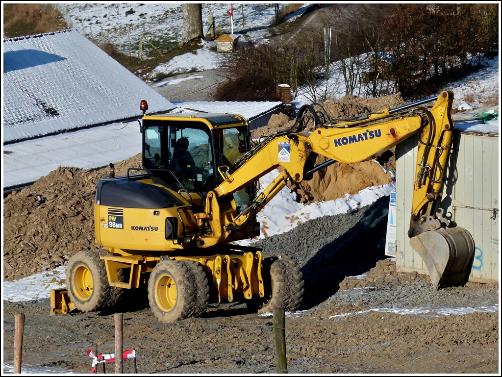 Radladerbagger Komatsu PW 98 MR steht bei eisiger Klte an einer Baustelle. 04.02.2012