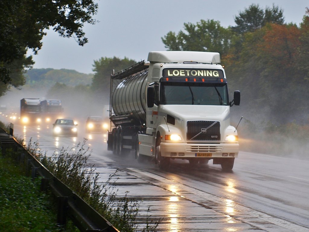 Volvo Hauber NH12 mit Tankauflieger am 19.10.2010 im strmenden Regen auf der A4 bei Aachen Richtung Niederlndische Grenze unterwegs. Im Hintergrund riskiert ein LKW Fahrer auf der linken Spur gerade 80 Euro und einen Punkt fr berholen im LKW berholverbot.