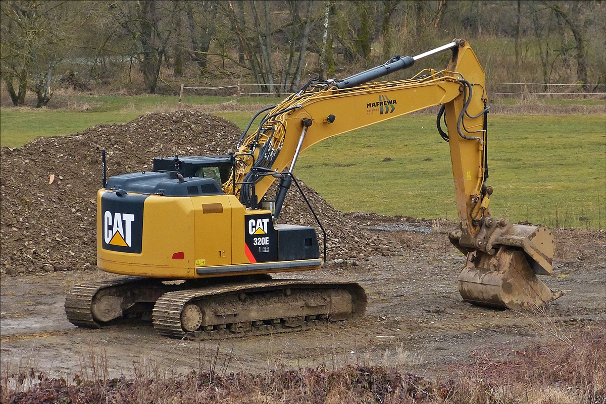 . Caterpillar 320E L RR Raupenbagger steht abseits von der Straße an einer Baustelle.  03.2018