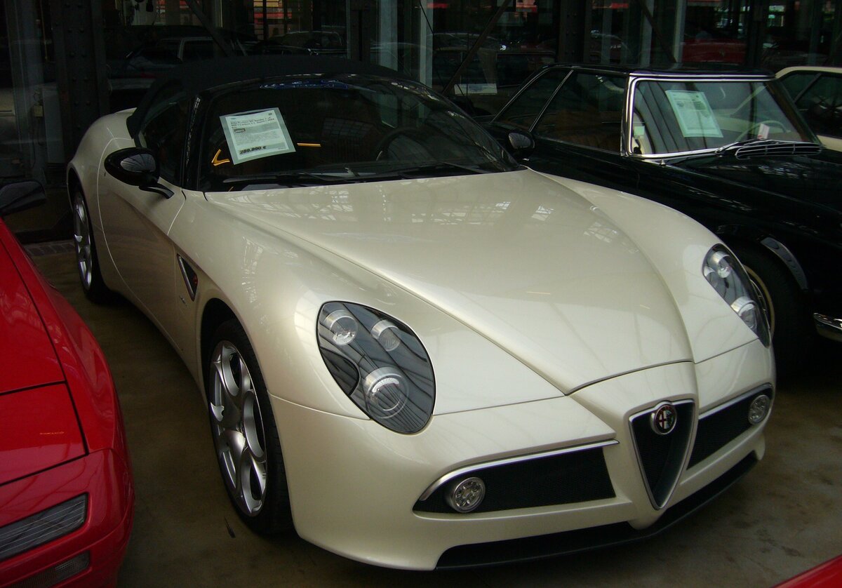 Alfa Romeo 8C Spider Competizione aus dem Jahr 2010. Zwischen 2008 und 2010 wurden genau 500 Alfa Romeo 8C Spider gebaut. Einen solchen Spider konnten man nicht einfach kaufen, sondern man musste sich als Interessent vormerken lassen. Bei Alfa Romeo wurde dann geprüft, ob man denn einen bekommt. Der Basispreis eines solchen 8C Spider betrug damals € 211.285,00. Der V8-Motor hat einen Hubraum von 4691 cm³ und leistet 450 PS. Dieser Spider, im Farbton bianco trofeo, stammt aus dem letzten Baujahr 2010. Der Wagen war übrigens ein gutes Investment, denn jetzt ruft der Verkäufer € 289.890,00 auf. Classic Remise Düsseldorf am 20.09.2023.