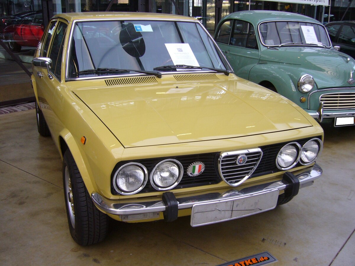 Alfa Romeo Alfetta 1.8 der Baujahre 1975 bis 1977. Die viertürige Alfetta Baureihe wurde 1972 als Nachfolger der Alfa Romeo Berlina Modelle am Markt platziert. Anangs wurde die Motorisierung vom Alfa Romeo 1750 übernommen. Im Jahr 1975 wurde das Modell auf den Namen Alfetta 1.8 umbenannt. Der Vierzylinderreihenmotor hat einen Hubraum von 1779 cm³ und leistet 118 PS. Die Höchstgeschwindigkeit gab das Mailänder Werk mit 180 km/h an. Die abgelichtete Alfetta im Farbton giallo piper (Pfeifengelb) wurde erstmalig im Januar 1977 zugelassen. Classic Remise Düsseldorf am 30.12.2022.