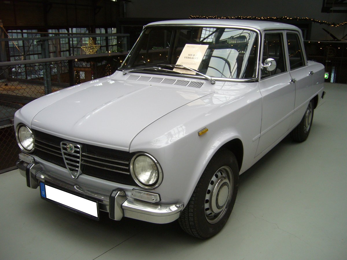 Alfa Romeo Giulia 1300 ti, gebaut von 1966 bis 1972. Mit der viertürigen Giulia hatte Alfa Romeo ab 1962 einen Verkaufsschlager gelandet. Es gab zum Verkaufsstart zwei Motorisierungen mit 1.3l und 1.6l Hubraum. Mit dem 1300 ti brachten die Mannen aus Milano ein sportliches Modell für den weniger betuchten Kunden auf den Markt. Der Vierzylinderreihenmotor mit doppelter Nockenwelle hat einen Hubraum von 1290 cm³ und leistet 82 PS. Classic Remise Düsseldorf am 26.11.2020.