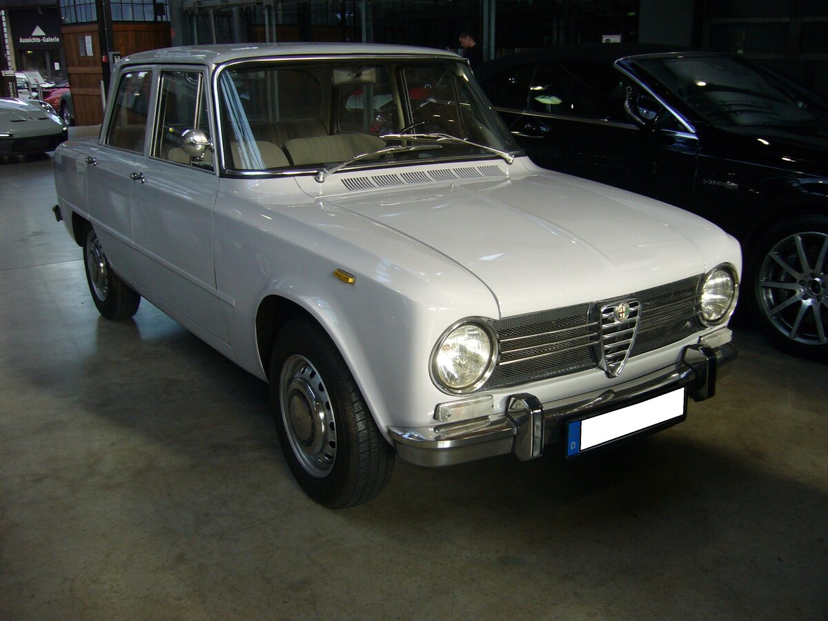 Alfa Romeo Giulia 1300 ti, gebaut von 1966 bis 1972. Mit der viertürigen Giulia hatte Alfa Romeo ab 1962 einen Verkaufsschlager gelandet. Es gab zum Verkaufsstart zwei Motorisierungen mit 1.3l und 1.6l Hubraum. Mit dem 1300 ti brachten die Mannen aus Milano ein sportliches Modell für den weniger betuchten Kunden auf den Markt. Der Vierzylinderreihenmotor mit doppelter Nockenwelle hat einen Hubraum von 1290 cm³ und leistet 82 PS. Classic Remise Düsseldorf am 21.10.2021.