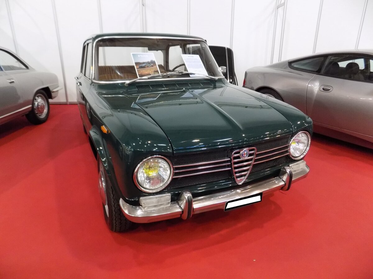 Alfa Romeo Giulia 1300 ti im Farbton verde pino, gebaut in den Jahren von 1966 bis 1972. Mit der viertürigen Giulia hatte Alfa Romeo ab 1962 einen Verkaufsschlager gelandet. Es gab zum Verkaufsstart zwei Motorisierungen mit 1.3l und 1.6l Hubraum. Mit dem 1300 ti brachten die Mannen aus Milano ein sportliches Modell für den weniger betuchten Kunden auf den Markt. Der Vierzylinderreihenmotor mit doppelter Nockenwelle hat einen Hubraum von 1290 cm³ und leistet 82 PS. Die gezeigte Giulia stammt aus dem Modelljahr 1969. Techno Classica Essen am 27.03.2022.