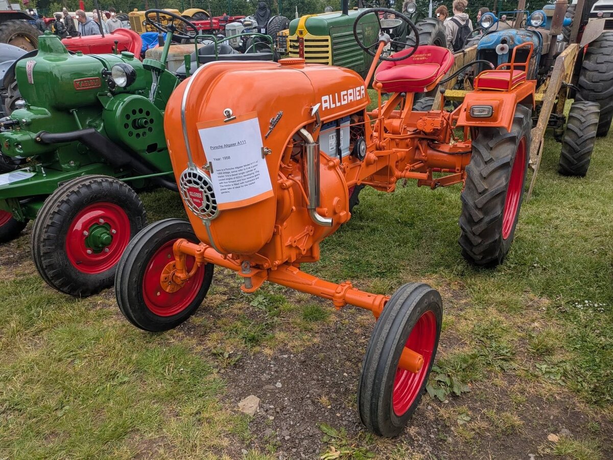 Allgaier A 111/System Porsche. Zwischen 1952 und 1955 wurde dieses Traktorenmodell in relativ gro�er St�ckzahl gebaut. Er war ein Meilenstein der landwirtschaftlichen Motorisierung in der Zeit nach WW2 und basiert direkt auf den Konstruktionen von Ferdinand Porsche. Nach WW2 durfte Porsche keine eigenen Traktoren bauen. Die Entw�rfe des bereits konstruierten  Volksschleppers  wurden daher als Lizenz an die Firma Allgaier im schw�bischen Uhingen vergeben. Der luftgek�hlte Einzylinderdieselmotor nach dem Zweitaktprinzip hat einen Hubraum von 822 cm� und leistet 12 PS. Castle Combe Vintage Show am 19.05.2024 in Wiltshire/England.