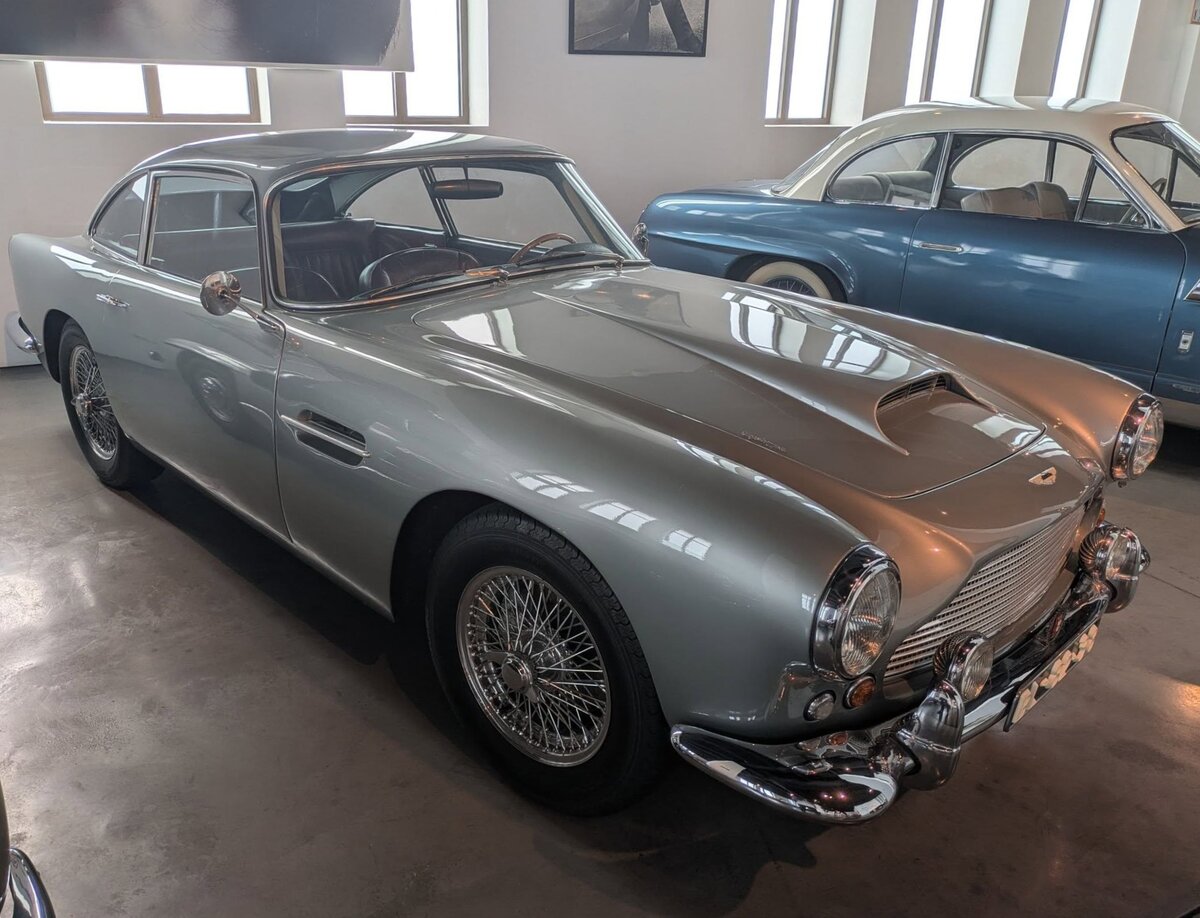 Aston Martin DB4. Gebaut wurden in den Jahren von 1958 bis 1963 genau 1.185 Fahrzeuge in 5 Serien. Dieser DB4 aus dem Jahr 1961 ist ein Fahrzeug der dritten Serie. Das  DB  in der Typenbezeichnung steht übrigens für David Brown, den Eigentümer/Gründer der Firma Aston Martin. Der Sechszylinderreihenmotor hat einen Hubraum von 3670 cm³ und leistet 243 PS. Die Höchstgeschwindigkeit betrug, je nach bestellter Getriebeübersetzung, zwischen 210 Km/h und 225 km/h. Museo Automovilistico de Malaga/Spanien am 22.03.2026.