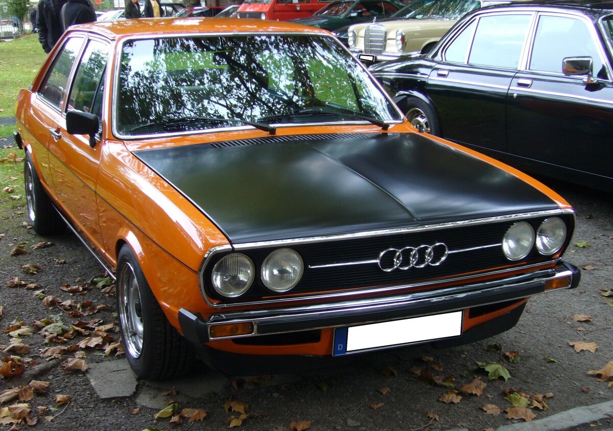 Audi B1 80 GTE, gebaut in den Jahren 1975 und 1976. Der GTE war das sportlichste Modell der bereits 1972 vorgestellten B1 Baureihe. Der Vierzylinderreihenmotor hat einen Hubraum von 1588 cm³ und leistet 100 PS. Bei einem Eigengewicht von 880 kg verhilft diese Motorisierung dem Wagen zu einer Höchstgeschwindigkeit von 173 km/h. Der gezeigte Wagen im Farbton cadizorange wurde 1976 erstmalig zugelassen. Oldtimertreffen beim Theater an der Niebu(h)rg am 22.10.2023 in Oberhausen.