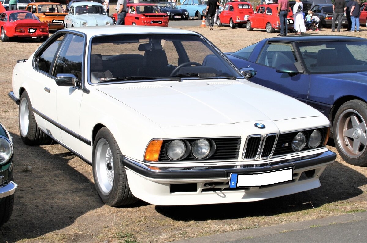 BMW E24 635CSi M6. Das BMW 6´er Coupe der Baureihe E24 wurde im März 1976 auf dem Genfer Auto Salon vorgestellt und bis 1989 produziert. Das Coupe war mit etlichen Motorisierungen lieferbar. Spitzenmodell war jedoch der abgelichtete 635 CSi M6, der ab Frühjahr 1984 bei den Händlern stand. Äußerlich unterscheidet er sich vom  normalen 635CSi  durch eine tiefer herunter gezogene Frontschürze. Unter der Haube ist der Motor des BMW M1 verbaut. Dieser Sechszylinderreihenmotor mit Vierventiltechnik hat einen Hubraum von 3453 cm³ und leistet 286 PS. Die Höchstgeschwindigkeit wurde von BMW mit 255 km/h angegeben. Für ein solches Auto waren bei seiner Markteinführung mindestens DM 102.050,00 fällig. 8. Oldtimertreffen des AMC Duisburg am 04.09.2022.