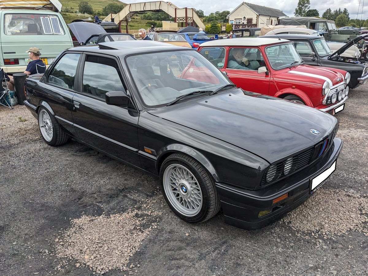 BMW E30 318is. Die Produktion des E30, also der zweiten Baureihe des 3´er BMW, begann im Oktober 1982. Ab August 1989 stand der gezeigte 318is bei den Vertragshändlern. Er blieb bis 1991 im Verkaufsprogramm der Münchener. Der Vierzylinderreihenmotor mit 16-Ventiltechnik hat einen Hubraum von 1796 cm³ und leistet 136 PS. Die Höchstgeschwindigkeit wurde mit 205 km/h angegeben. Auch äußerlich kam der 318is sportlich daher. Er war serienmäßig mit einem speziellen Front- und Heckspoiler, sportlichem Interieur und speziellen Alu-Felgen ausgestattet. September 2024 auf dem Besucherparkplatz eines Pubs in Pont-Neddfechan/South Wales.