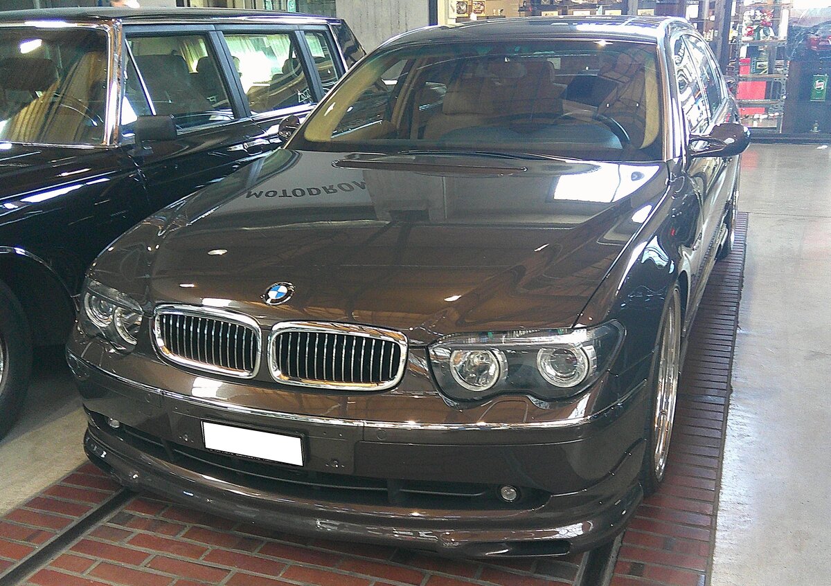 BMW E65 760Li. Die Baureihe E65 steht für die vierte Generation der so genannten 7´er Reihe aus dem Hause BMW. Der hier gezeigte 760Li im Farbton moccabraun metallic war das absolute Toppmodell dieser Baureihe. Insbesondere bei der Innenausstattung hebt sich das Spitzenmodell von den  gewöhnlichen  7´ern ab. Beim Einstieg ins Auto wird man von einem beleuchteten V12 Schriftzug begrüßt. Des Weiteren hebt sich der 760 Li durch eine extrem aufwendige Verarbeitung und edle Materialien ab. Hierbei stand Vollleder im Vordergrund. Das Armaturenbrett und alle Türtafeln wurden aufwendig mit Leder bezogen und die Türtaschen mit Nähten eingefasst. Ebenso ist die Mittelkonsole in Vollleder mit Ziernähten gehalten. Die Handinnengriffe wurden mit Nussbaum-Wurzelholz-Einlage versehen, anstatt in der Standard-Ausführung mit Kunststoff. Das Wurzelholz-Interieur ist mit Intarsien verziert. Der V12-Motor hat einen Hubraum von 5972 cm³ und leistet 445 PS. Bei einer Geschwindigkeit von 250 km/h wird automatisch abgeriegelt. Classic Remise Düsseldorf am 02.03.2026.