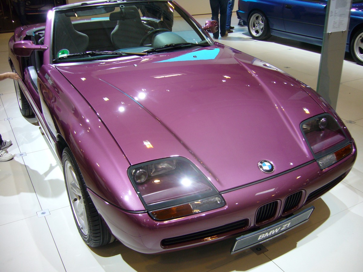 BMW Z1. 1989 - 1991. 1986 überraschte BMW die Fachwelt mit einem modernen Prototyp. In aller Stille hatte die BMW Technik GmbH einen futuristisch gestylten Sportzweisitzer mit Kunststoffkarosserie fast zur Serienreife entwickelt. Dieser Roadster erregte soviel Interesse, dass BMW ab Ende 1988 eine Kleinserie von 8000 Stück auflegte. Mit der Antriebstechnik des BMW 325i und technischen Finessen, wie den versenkbaren Türen, entwickelte das Auto sich auf Anhieb zum Liebhaberstück. Der 6-Zylinderreihenmotor leistet aus 2494 cm³ Hubraum 170 PS. Der abgelichtete Wagen trägt die nur 228 mal bestellte Lackierung magic-violet. Techno Classica am 18.04.2015.