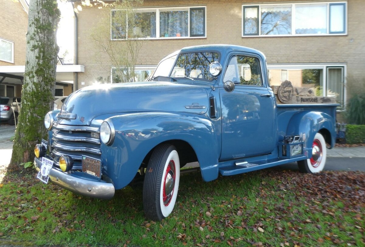 Chevrolet 3100 Pickup Truck aus dem Jahr 1951 im Farbton windsor blue. Die Series 3100 Truck-Modelle wurden im Mai 1947 von Chevrolet als neue Nutzfahrzeug-Linie vorgestellt. Dieses völlig neu konstruierte Modell ersetzte die Chevrolet AK-Serie, die ab 1941 produziert wurde. Typisch für diese Trucks waren, die in die vorderen breiten Kotflügel integrierten Scheinwerfer und die hohe Motorhaube. Bis ins Modelljahr 1953 hatte das Modell auch noch eine geteilte Windschutzscheibe. Das als Unisteel-Kabine bezeichnete Führerhaus des Chevrolet 3100 im so genannten  Advance Design  besaß eine durchgehende Sitzbank mit verstellbaren Sitzpositionen, die reichlich Platz für drei Personen bot. Ab dem Modelljahr 1954 wurden diese 0.75to Trucks mit den neuen  Stovebolt-Engines  ausgerüstet. Diese Sechszylinderreihenmotoren konnten wahlweise mit 3.9l oder 4.3l Hubraum bestellt werden. Des weiteren hatte der Kunde die Wahl zwischen einem 3-Gang oder 4-Gang-Getriebe. Die Konkurrenten auf dem US-Markt waren damals die ähnlich gestalteten Ford F 100 und die Dodge B-Series Pickups. In der Nähe von Enschede/NL am 15.10.2023.