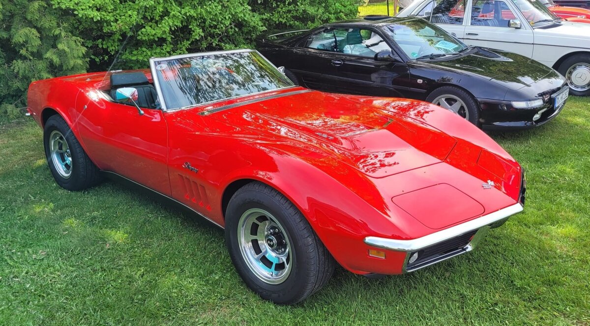 Chevrolet Corvette C3 Stingray Roadster im Farbton monza red aus dem Jahr 1969. Dieses Modell geh�rt zu den begehrtesten Jahrg�ngen der legend�ren  Shark-Generation“. Das Modelljahr 1969 gilt unter Sammlern als besonders wertvoll, da in diesem Jahr der ikonische Schriftzug  Stingray“ (erstmals in einem Wort geschrieben) auf den vorderen Kotfl�geln zur�ckkehrte und die klassischen Chromelemente an Front und Heck noch vollst�ndig vorhanden waren. Die Roadster-Variante bot ein komplett versenkbares Stoffverdeck. Gegen Aufpreis war ab Werk ein abnehmbares Hardtop erh�ltlich. Bei der Motorisierung konnte der Kunde aus einer gro�en Auswahl von V8-Motoren w�hlen: : Vom klassischen Small-Block-V8 mit einem Hubraum von 350 cui (5735 cm�) mit Leistungen von 300 PS bis 350 PS, bis hin zu den legend�ren Big-Block-V8-Motoren mit einem Hubraum von 427 cui (6977 cm�), darunter das Tri-Power-Modell L71 mit brachialen 435 PS. Oldtimertreffen Altenthann/Oberpfalz am 03.05.2026.
