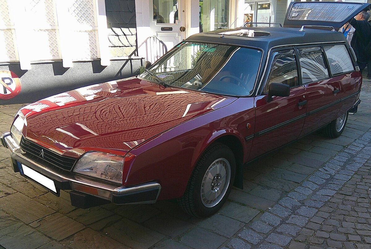 Citroen CX2500 Bestattungswagen aus dem Jahr 1984. Der Citro�n CX 2500 Rappold-Leichenwagen ist ein Bestattungsfahrzeug, der auf dem Citro�n CX Break (Kombi) basiert und von der renommierten Firma Rappold in W�lfrath/Kreis Mettmann/NRW umgebaut wurde. Diese Fahrzeuge sind f�r ihr au�ergew�hnliches Design, den hohen Fahrkomfort dank der Hydropneumatik und die gro�z�gigen Platzverh�ltnisse bekannt. Rappold nutzte f�r den Umbau oft unverl�ngerte CX Break-Modelle, da diese bereits eine sehr gro�e L�nge aufwiesen. Laut dem Besitzer ist in diesem  Bestatter  der Vierzylinderreihenmotor des Citroen CX2500 verbaut. Dieser hat einen Hubraum von 2499 cm� und leistet, je nach Baujahr und ob mit oder ohne Turbo, zwischen 123 PS und 168 PS. 18. Oldtimer Fr�hling des AMC Kettwig am 01.05.2026 in Essen Kettwig.