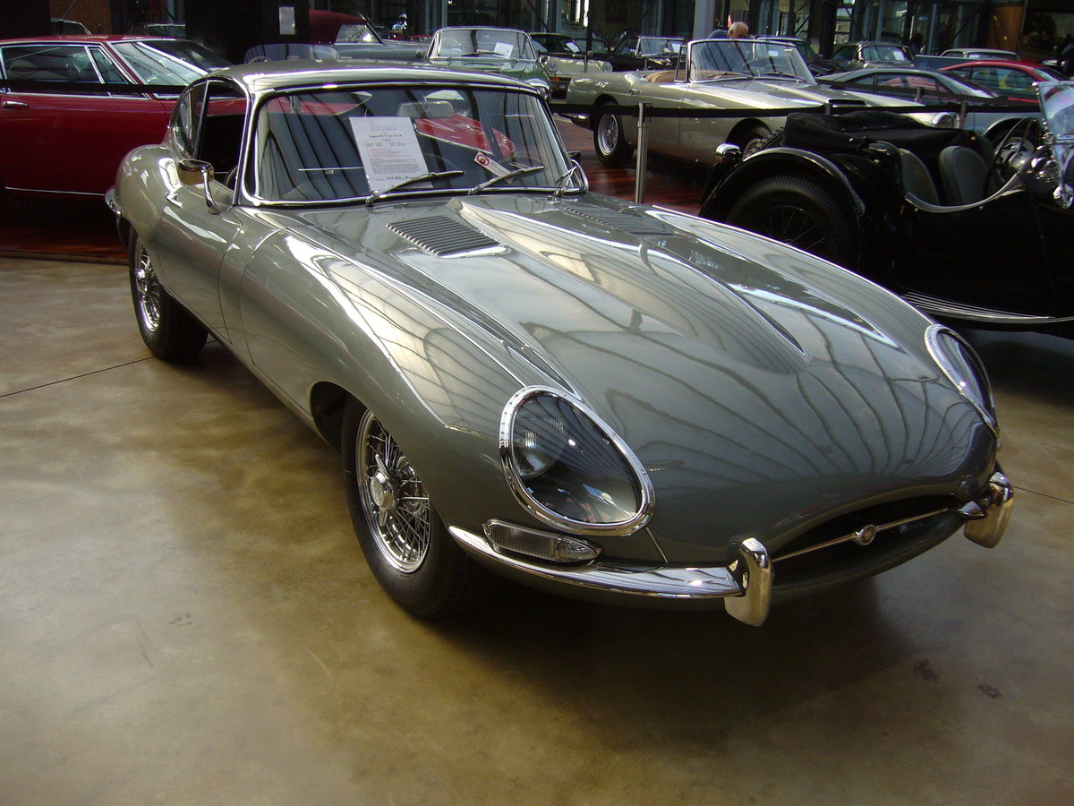 Der E Type, ein Klassiker par excellence im Farbton opalescent grey. Vorgestellt auf dem Genfer Salon des Jahres 1961. Wie schon 13 Jahre zuvor der XK120 stieß auch der E Type in der Fachpresse auf einhellige Begeisterung. Sowohl Cabriolet, als auch das FHC (Fixed Head Coupe) genannte, geschlossene Modell waren sofort der Traumwagen der breiten, automobilen Masse. Obwohl die Warteliste bzw. Lieferzeit lang war, bot der damalige Jaguar-Boss William Lyons den Wagen zu einem unerwartet günstigen Preis an. Der Sechszylinderreihenmotor des Series I hat einen Hubraum von 3781 cm³ und leistet 265 PS. Die Höchstgeschwindigkeit des Series I betrug 237 km/h. Classic Remise Düsseldorf am 24.02.2018.