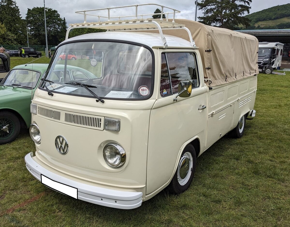 Ein rechts gelenkter VW T2b Pritschenwagen aus dem Jahr 1976. Im August 1967 brachte Volkswagen den, in Form und Technik durchgreifend modernisierten, Transporter der zweiten Generation auf den Markt. Das Modell wurde allgemein nur T2a genannt. Im August 1972 erfolgte ein Facelift. Äußerlich erkennbar war dieses Modell an den vorderen Blinkleuchten in Höhe der Lüftungsschlitze und den  Eisenbahnschienen  genannten Stoßfängern. Im Heck verrichtete ein Gebläse-gekühlter Vierzylinderboxermotor mit einem Hubraum von 1584 cm³ und einer Leistung von 50 PS seinen Dienst. Steam and vintage show am 27.05.2024 in Abergavenny/South Wales.